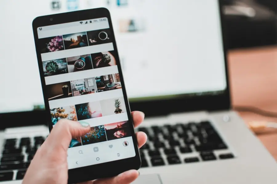 Smartphone con un feed social davanti a un portatile